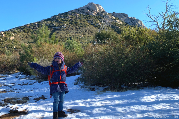 Girl hiking in snow with arms outstretched.