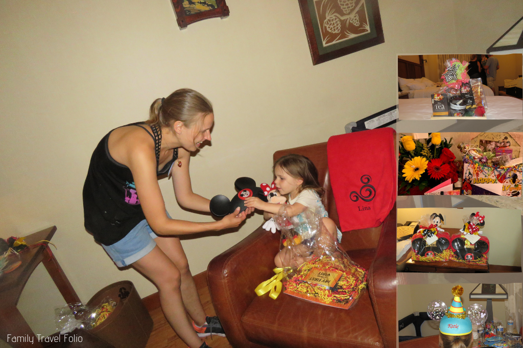 Mom helping toddler girl open First Time at Disney gift package including Mickey Mouse ears hat and personalized Mickey Mouse Blanket. Smaller photos overlay the image and show the Tea Gift Package, Birthday Package, Birthday Ears hat, and wrapped up Mickey and Minnie First Visit gift packages.
