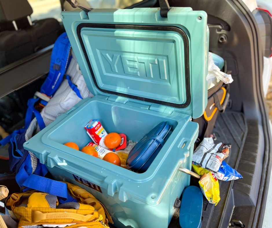 Yeti cooler open in trunk of car showing ice and food inside