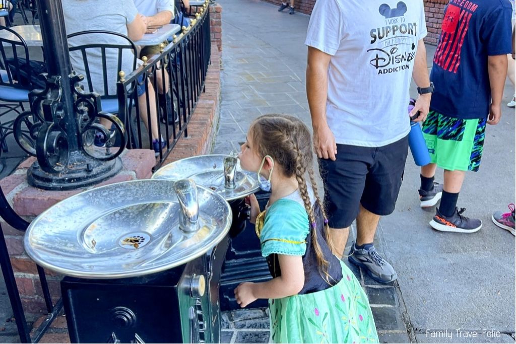 Little girl drinking from water fountain in New Orleans Square.