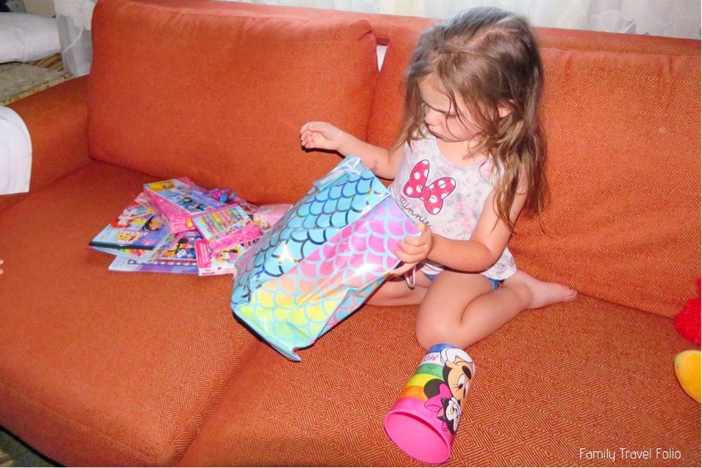 Disneyland Cheap Vacations: Dollar Tree Disney Items. Toddler girl taking Disney themed craft supplies out of bag on hotel couch.