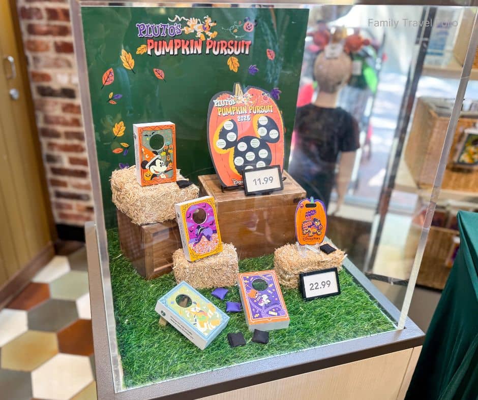 Pluto's Pumpkin Pursuit 2025 prize display in a shop—game maps and souvenir prizes with prices—perfect for Disneyland’s Halloween season.