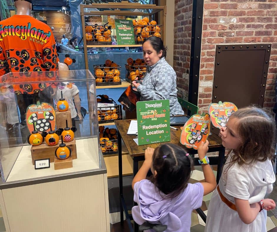 Two young girls turning in their completed Pluto's Pumpkin Pursuit maps at the redemption location in Downtown Disney for their prize.