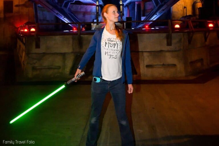 Woman wearing Disney Mom t-shirt and holding green light saber at Disneyland
