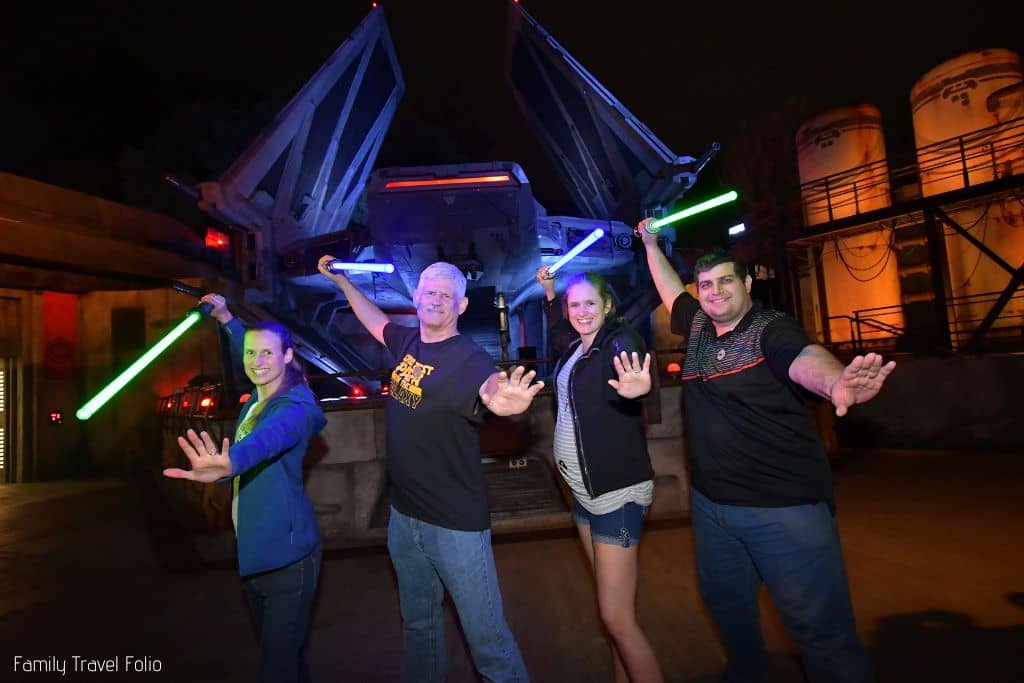 4 adults holding light sabers at Disneyland