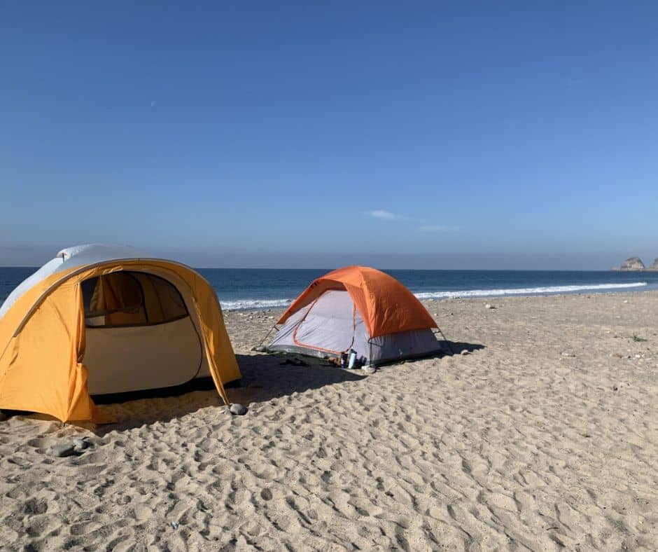 two tents on beach with ocean in background