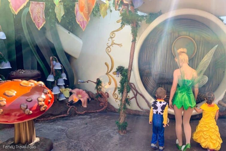 Tinkerbelle with toddler boy and girl in front of her house at Disneyland