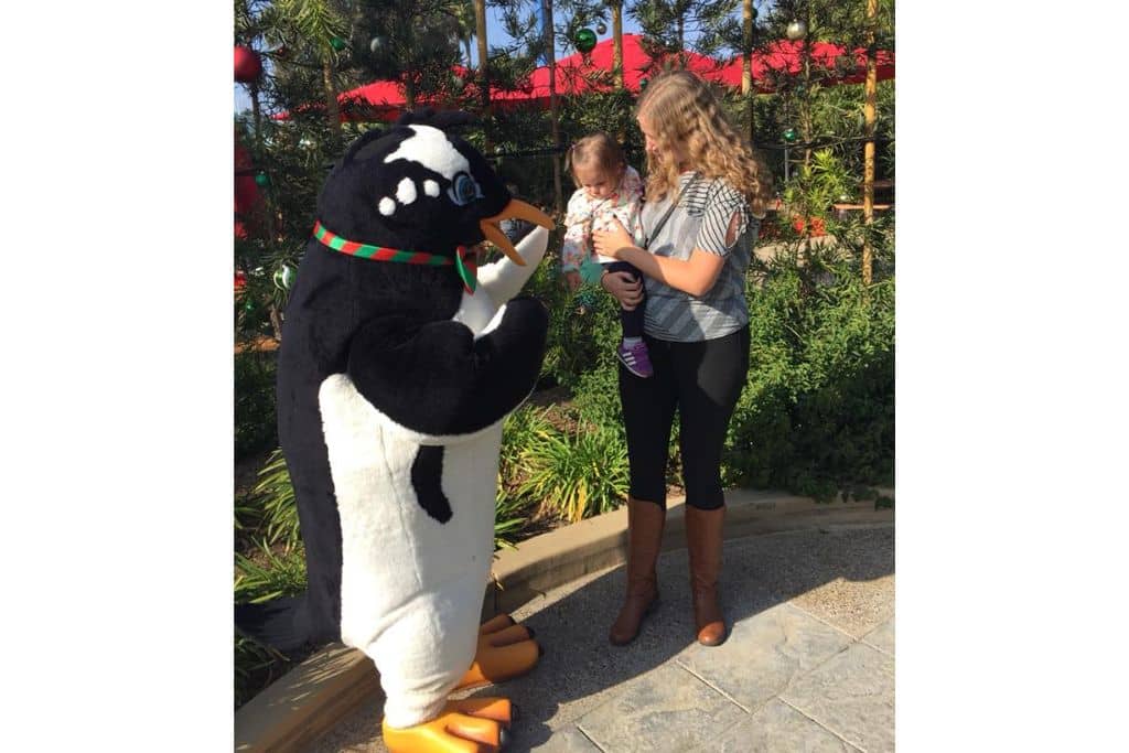 Toddler girl being held by aunt, Meeting costumed Penguin character at SeaWorld
