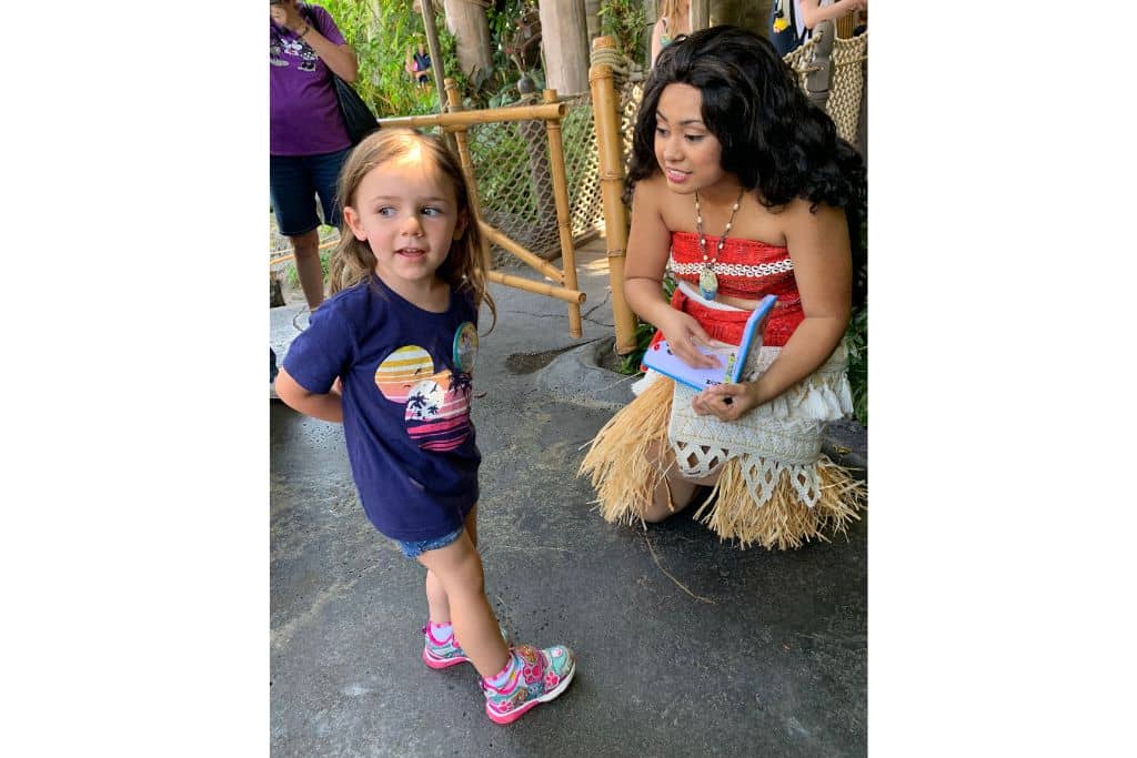 Toddler girl talking to Moana at Disneyland as she signs the autograph book