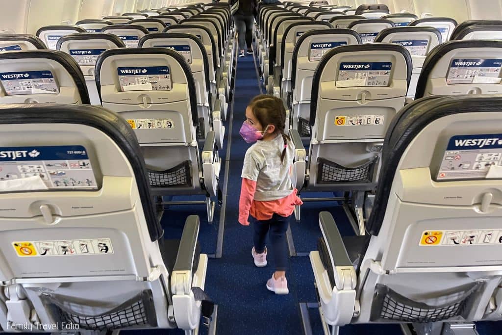 Toddler girl walking to seat on airplane.