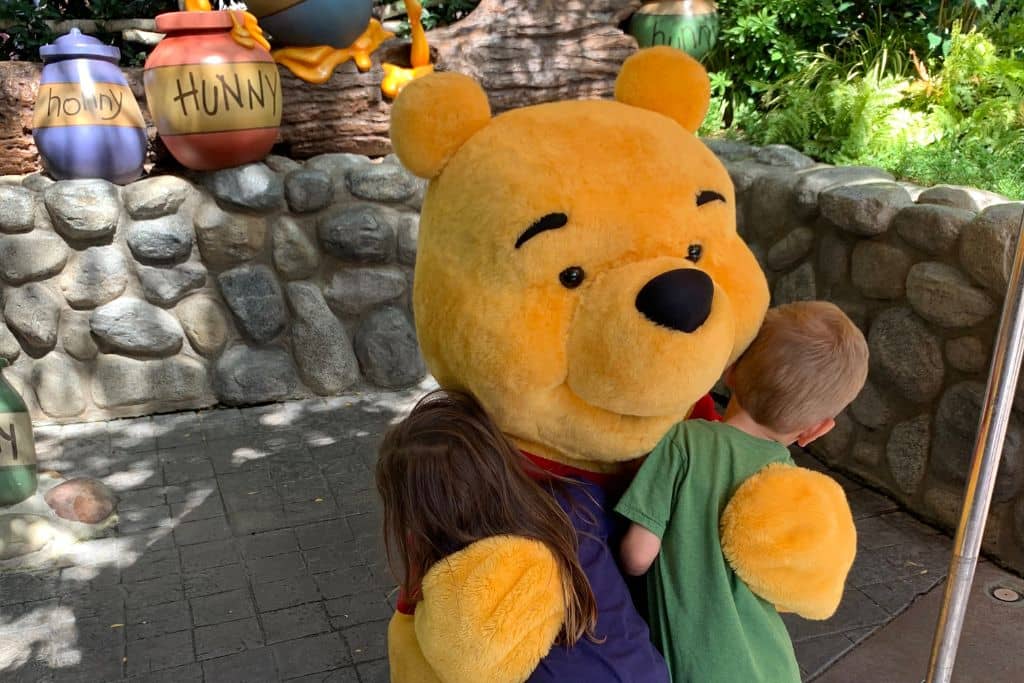 Boy and girld toddlers hugging Pooh at Pooh's Corner in Disneyland