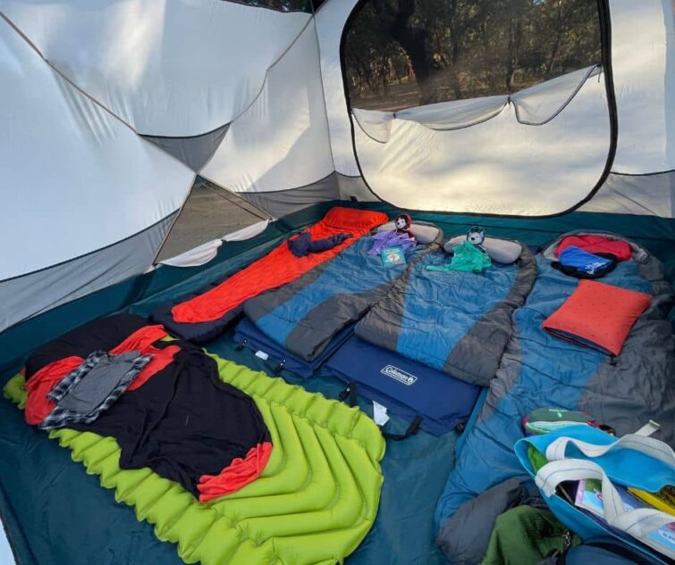 Picture of inside of tent with camping mattresses and sleeping bags: 4 across with 1 along the bootom