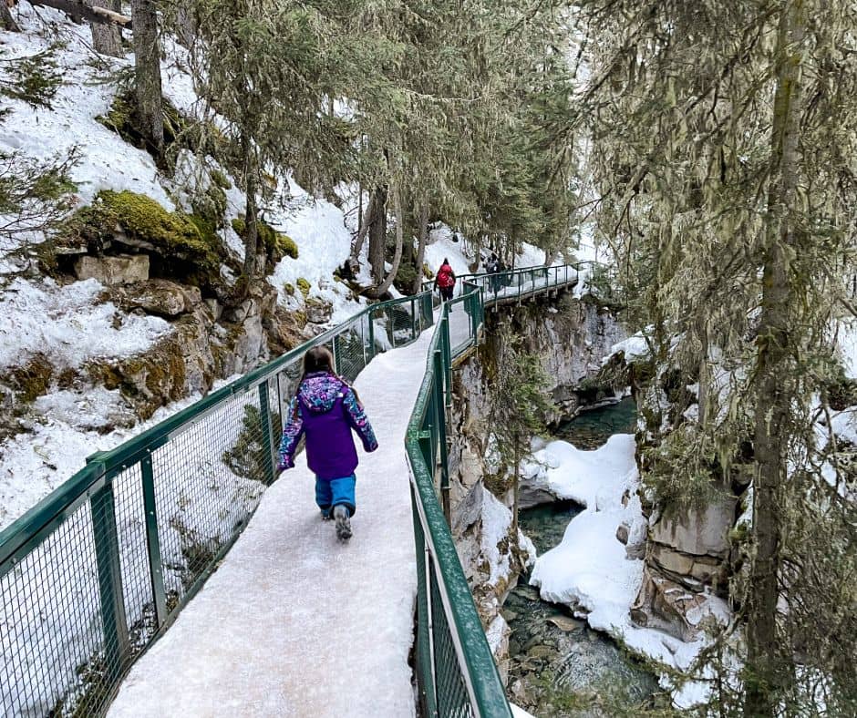 Walking along snow and ice covered bridge trail to Johnston Canyon to Upper Falls