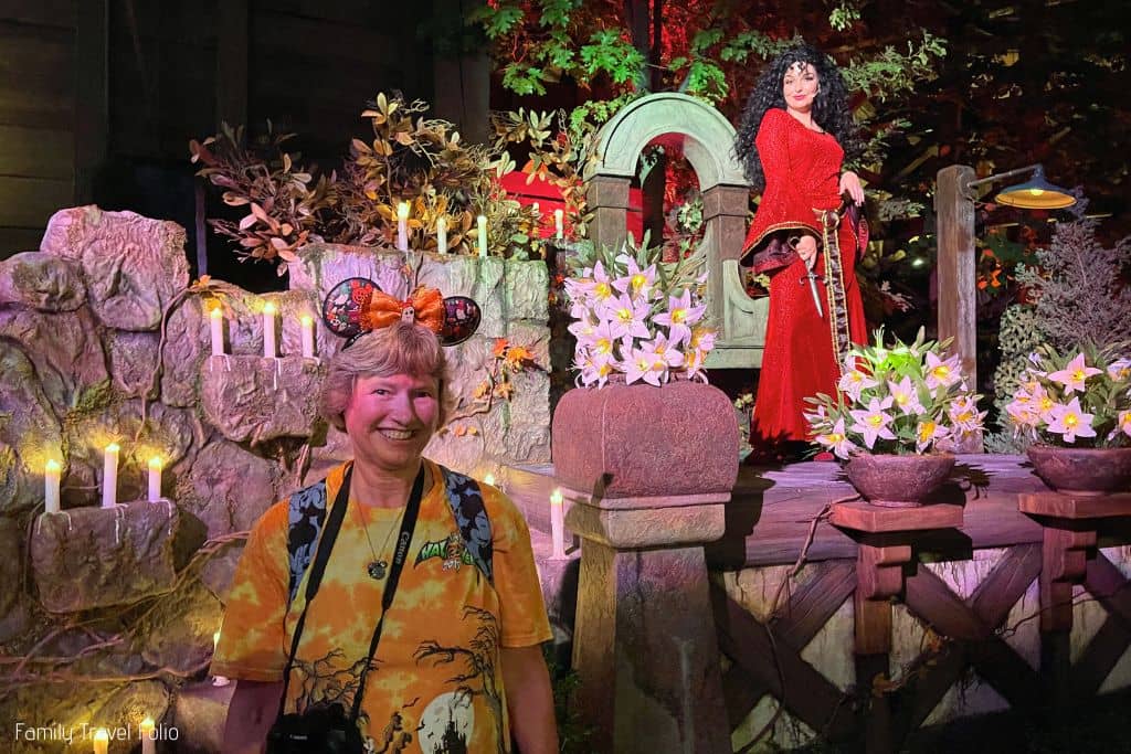 Woman smiling for photo with Mother Gothel on stage behind her