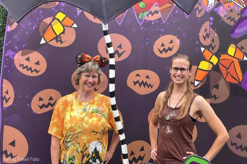 Halloween candy and pumpkin backdrop with woman and her mother posing for photo