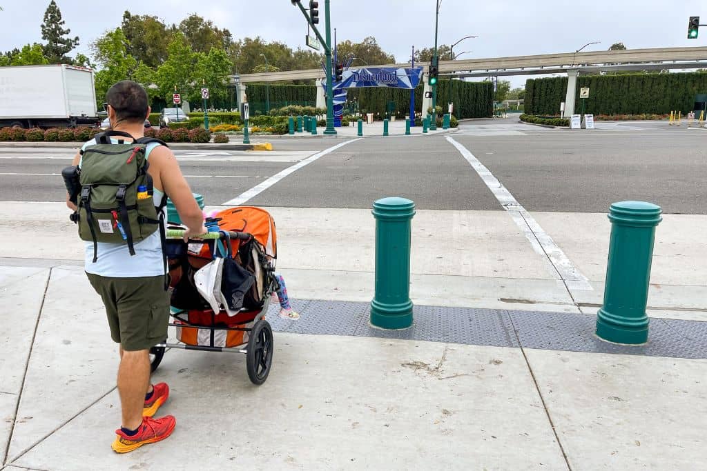 dad pushing stroller across the street to Disneyland