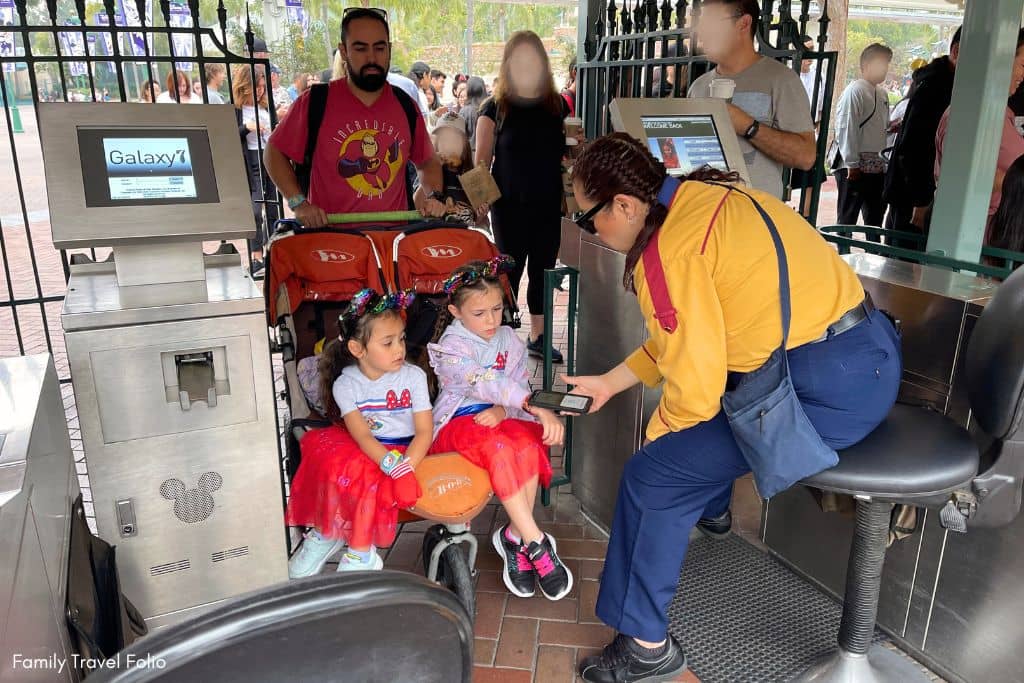 Little girls sitting in stroller scanning Magic Band Plus for entering Disneyland