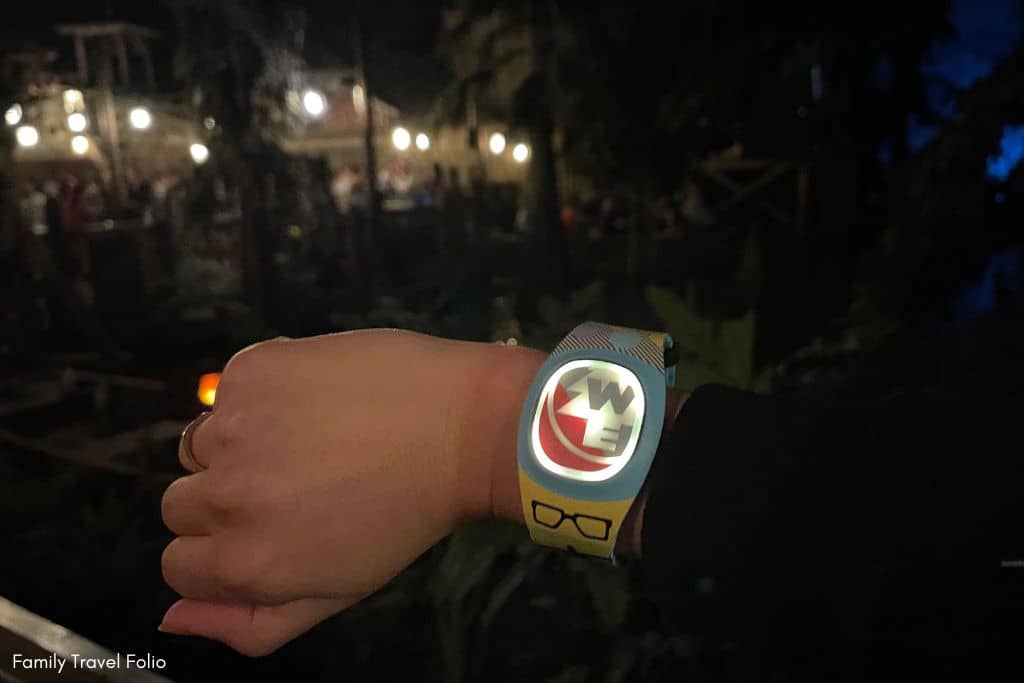 MagicBand+ Pirates Interaction white light glowing on band with Blue Bayou restaurant in background