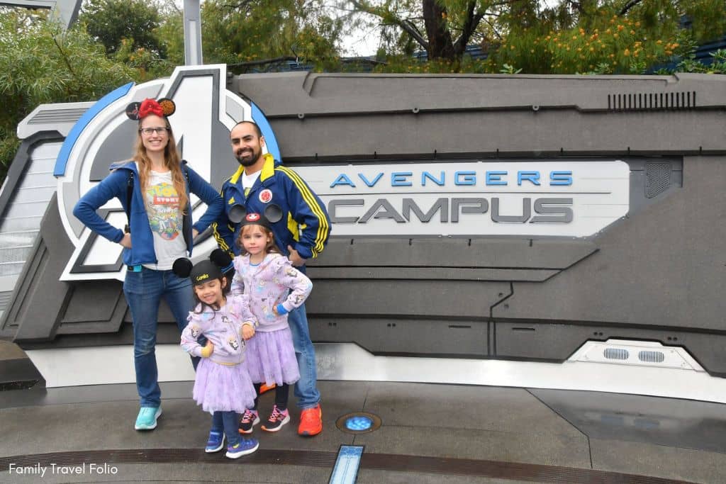 PhotoPass MagicBand family photo in front of Avenger's campus sign.