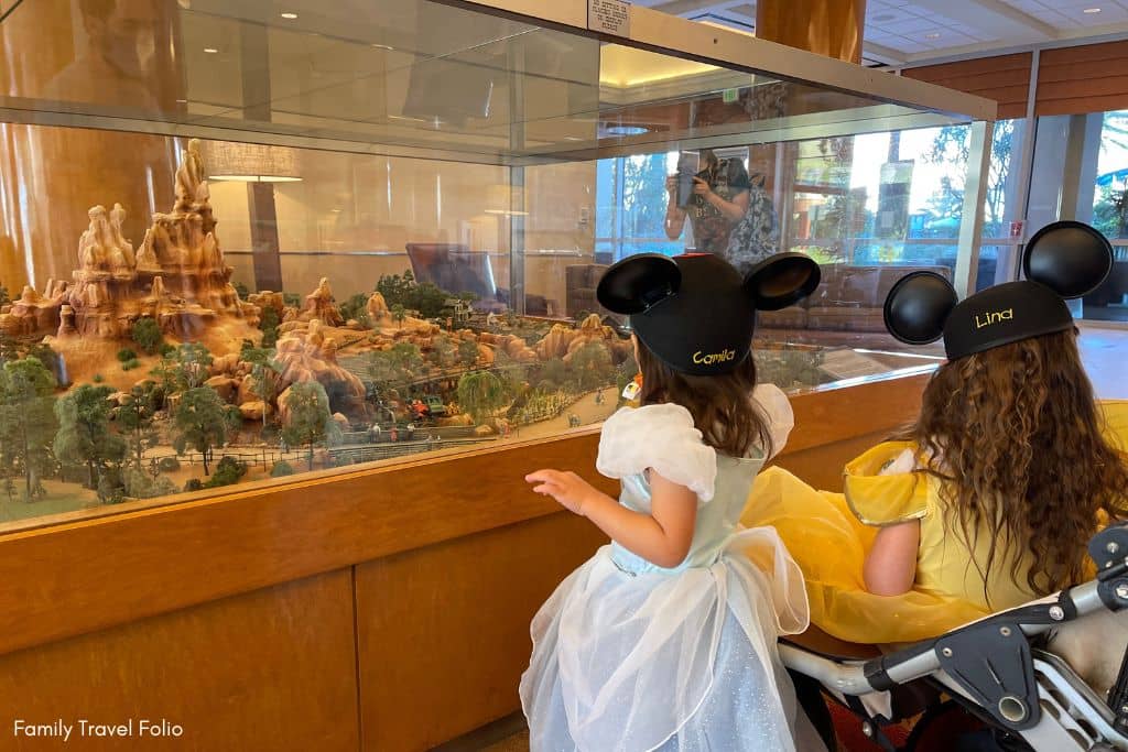 Two children in Disney costumes marvel at a miniature replica of a Disney attraction inside the Disneyland Hotel.