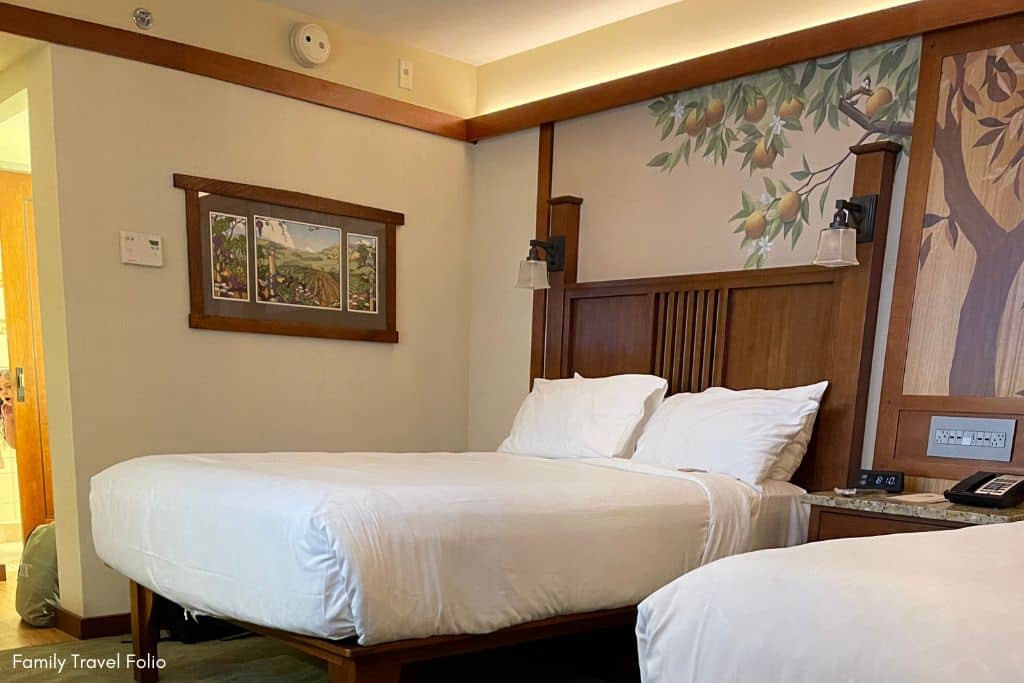 Inviting Grand Californian Hotel room with warm wood accents and nature-inspired artwork above the beds.