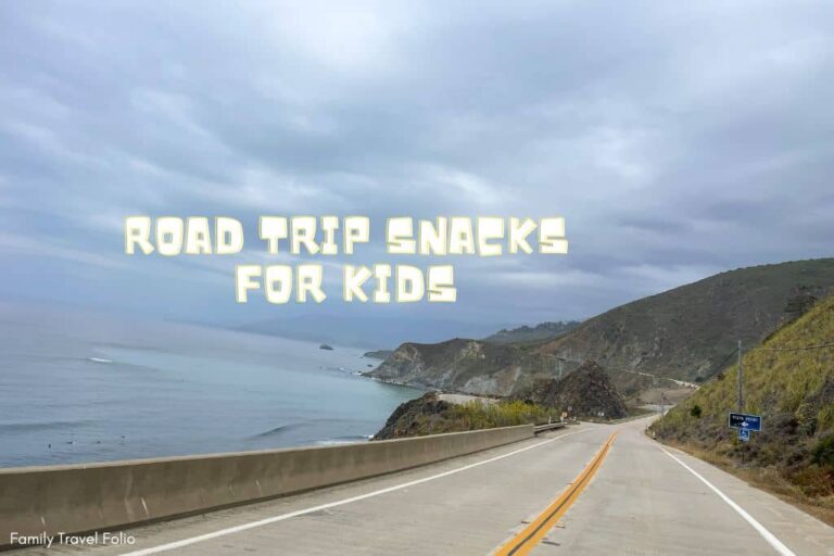Scenic coastal road with the text 'Road Trip Snacks for Kids' overlaying, inviting readers to learn about travel-friendly snack ideas.
