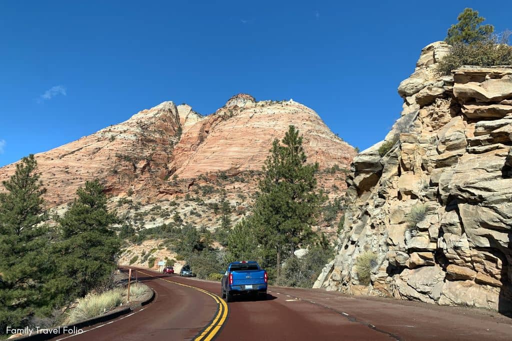 Family car driving through Zion National Park with breathtaking red rock formations, perfect for exploring with kids.