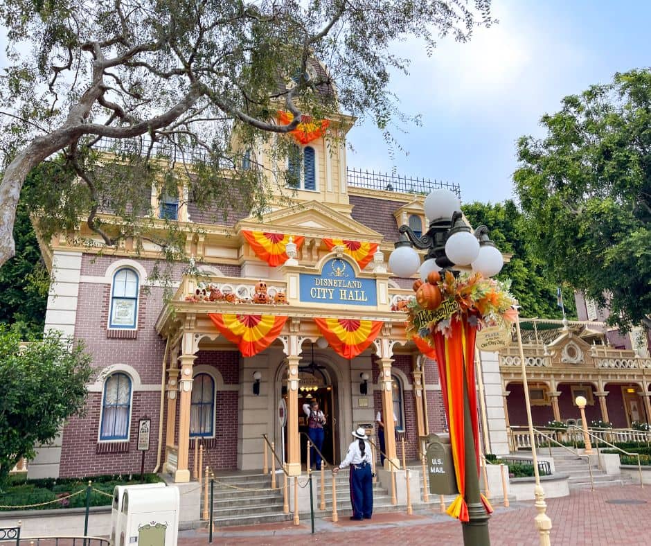 City Hall at Disneyland draped in orange and yellow Halloween decorations, capturing the festive October atmosphere in the park.