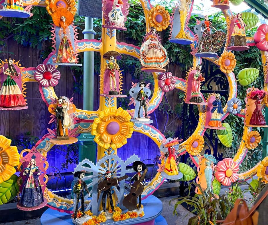 Colorful Día de los Muertos figurines displayed at Plaza de la Familia, featuring skeletons in traditional Mexican clothing as part of Disney's 'Coco'-themed celebration during October.