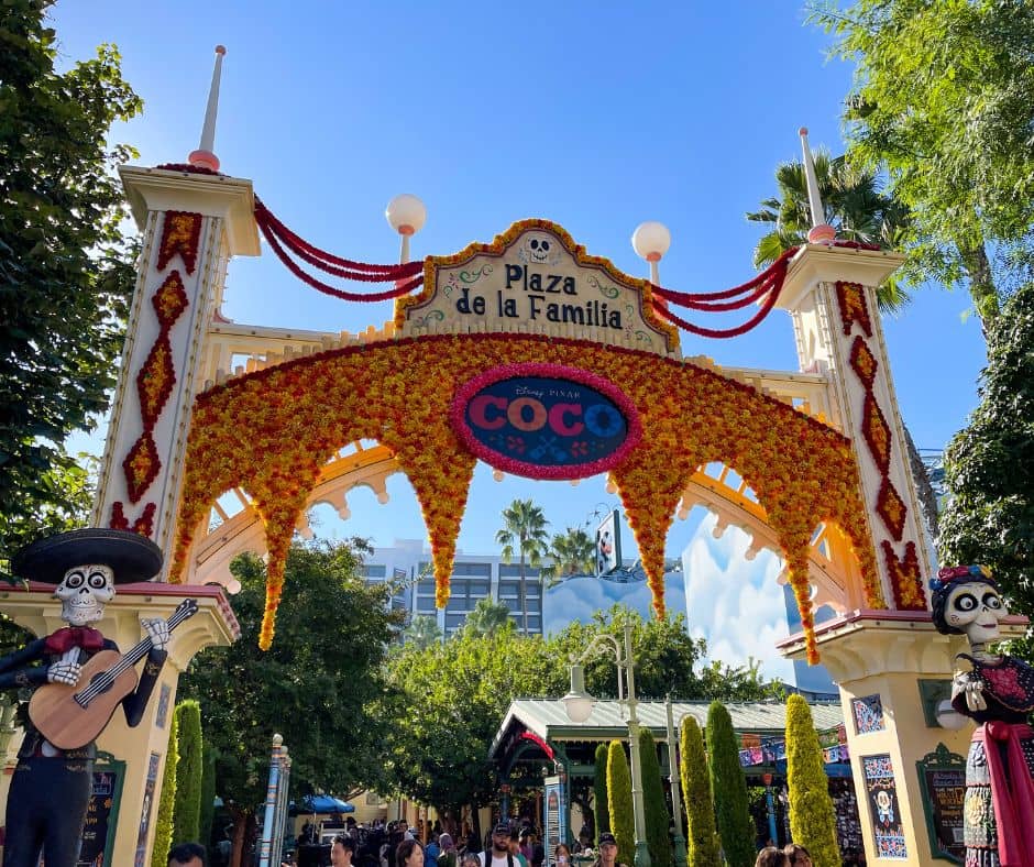 The vibrant entrance arch to Plaza de la Familia at Disney California Adventure, adorned with marigolds and 'Coco' decorations, celebrating Día de los Muertos during Disneyland's October festivities.