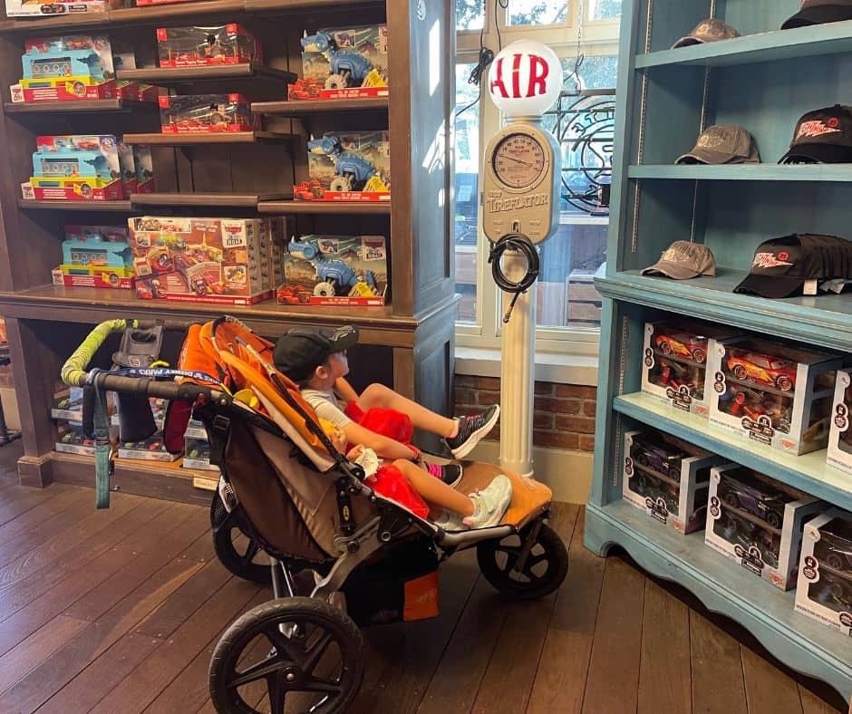 Child relaxing in a stroller inside a Disneyland store, taking advantage of the air conditioning to cool down during a hot day at Disneyland.