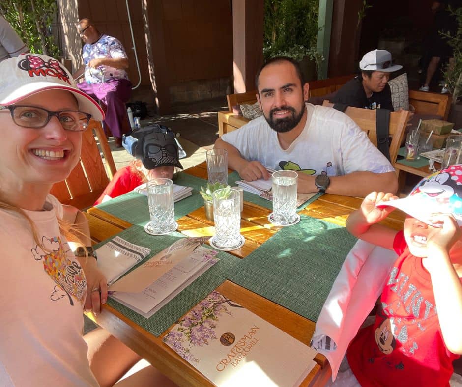 Family dining poolside at the Grand Californian's Craftsman Bar & Grill, taking a break from the heat with cool drinks and shaded seating.