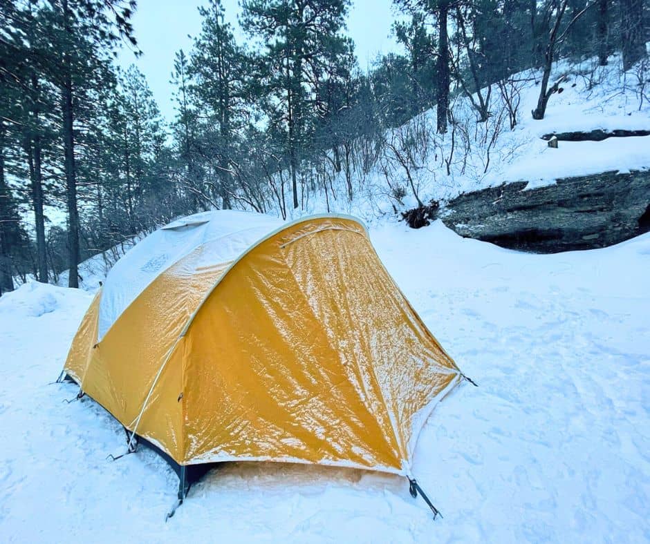 Yellow tent covered in frost and snow during a cold winter camping trip.