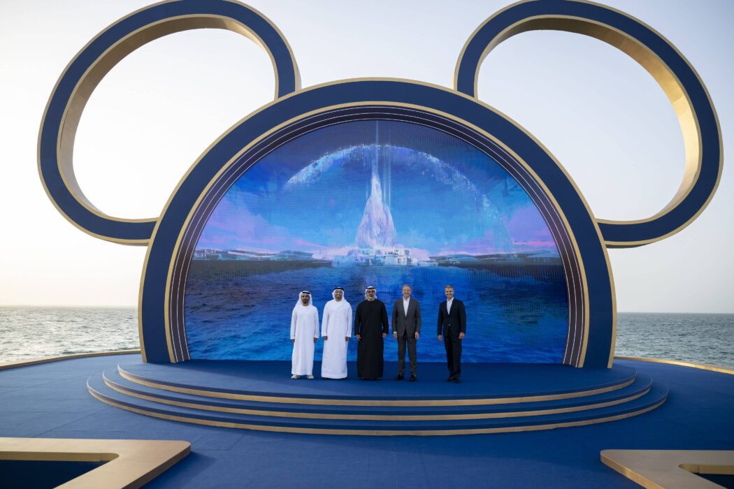 Disney executives and UAE leaders stand in front of a large Mickey-shaped stage at the Abu Dhabi Disneyland announcement.