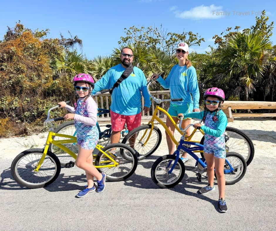 Family of four on beach cruiser bikes – Affordable family vacation activity idea for outdoor exploration.