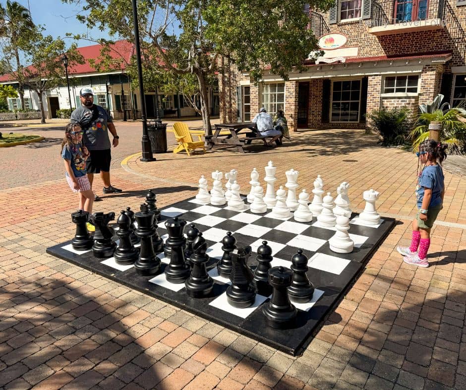 Children playing giant outdoor chess with father – Low-cost family activity while traveling.