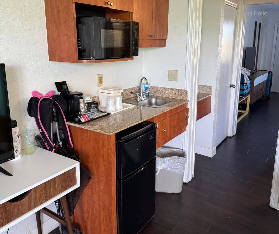 Small hotel kitchenette with microwave, mini fridge, and coffee maker – Budget tip for family vacation accommodation with in-room cooking options.