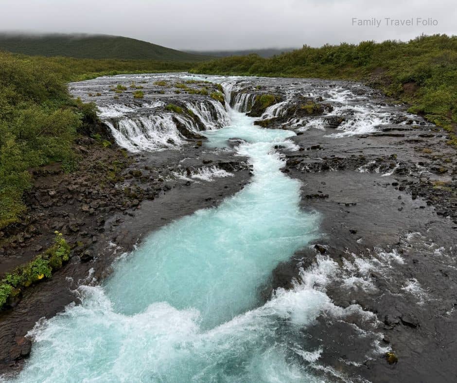 A stunning view of Brúarfoss waterfall with its vivid blue water cascading through rocky terrain, a must-see stop on the Golden Circle and one of the scenic things to do in Reykjavik.