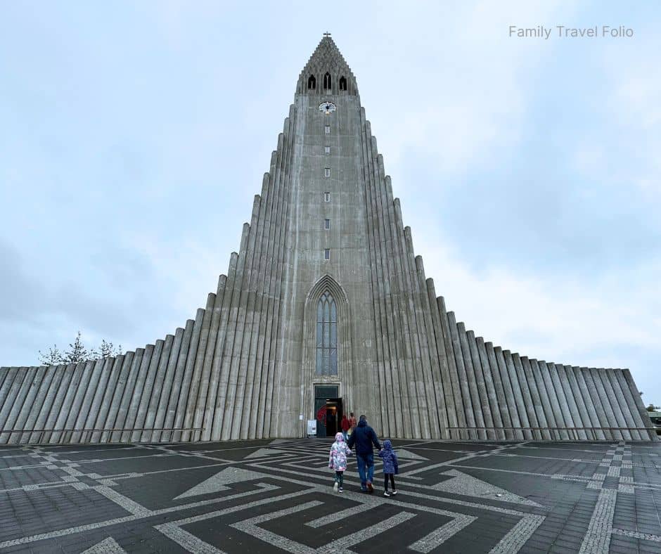 Family walking toward Hallgrímskirkja Church in Reykjavik, Iceland’s most famous architectural landmark and one of the must-see things to do in Reykjavik.