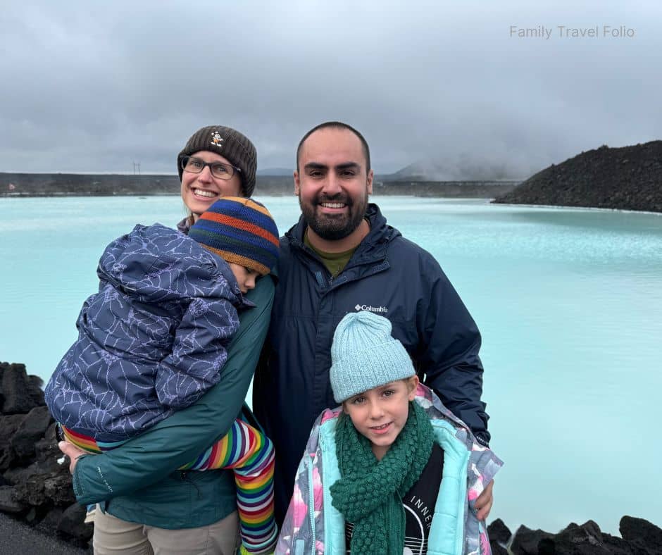 Family bundled in jackets smiling beside the milky-blue geothermal waters of the Blue Lagoon near Reykjavik, highlighting one of the most iconic and relaxing things to do in Reykjavik for visitors year-round.